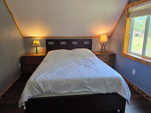 A bedroom with a bed, two bedside tables, a window, and a lamp.