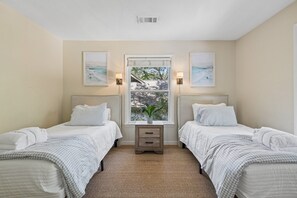 A bedroom with two beds, a window with a view, and wall-mounted lamps. - Spacious 5BR Home with Private Pool & 11-Mile Lagoon Views (Hilton Head Island)