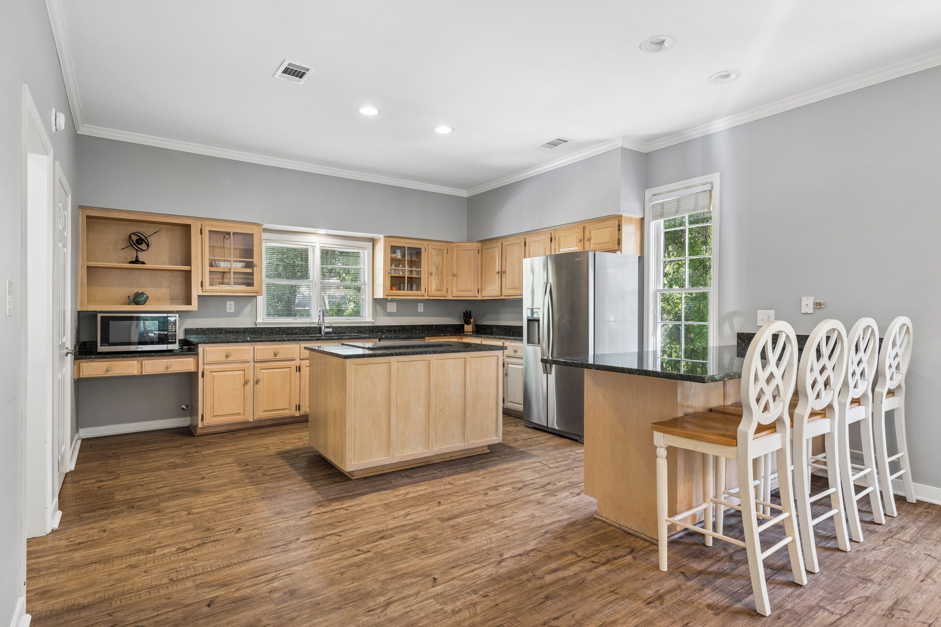 Una cocina moderna con armarios de madera, un refrigerador de acero inoxidable y una isla central.