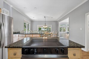 A kitchen with a central island, stainless steel appliances, and a dining area with a chandelier. - Spacious 5BR Home with Private Pool & 11-Mile Lagoon Views (Hilton Head Island)