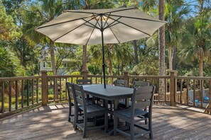 A deck with a table and chairs, surrounded by a wooden railing, overlooking a pond and greenery. - Spacious 5BR Home with Private Pool & 11-Mile Lagoon Views (Hilton Head Island)