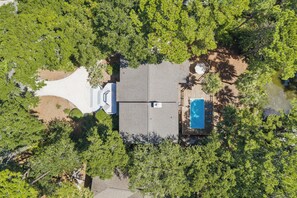 An aerial view of a property with a swimming pool, a covered patio, and a large open space surrounded by dense trees. - Spacious 5BR Home with Private Pool & 11-Mile Lagoon Views (Hilton Head Island)