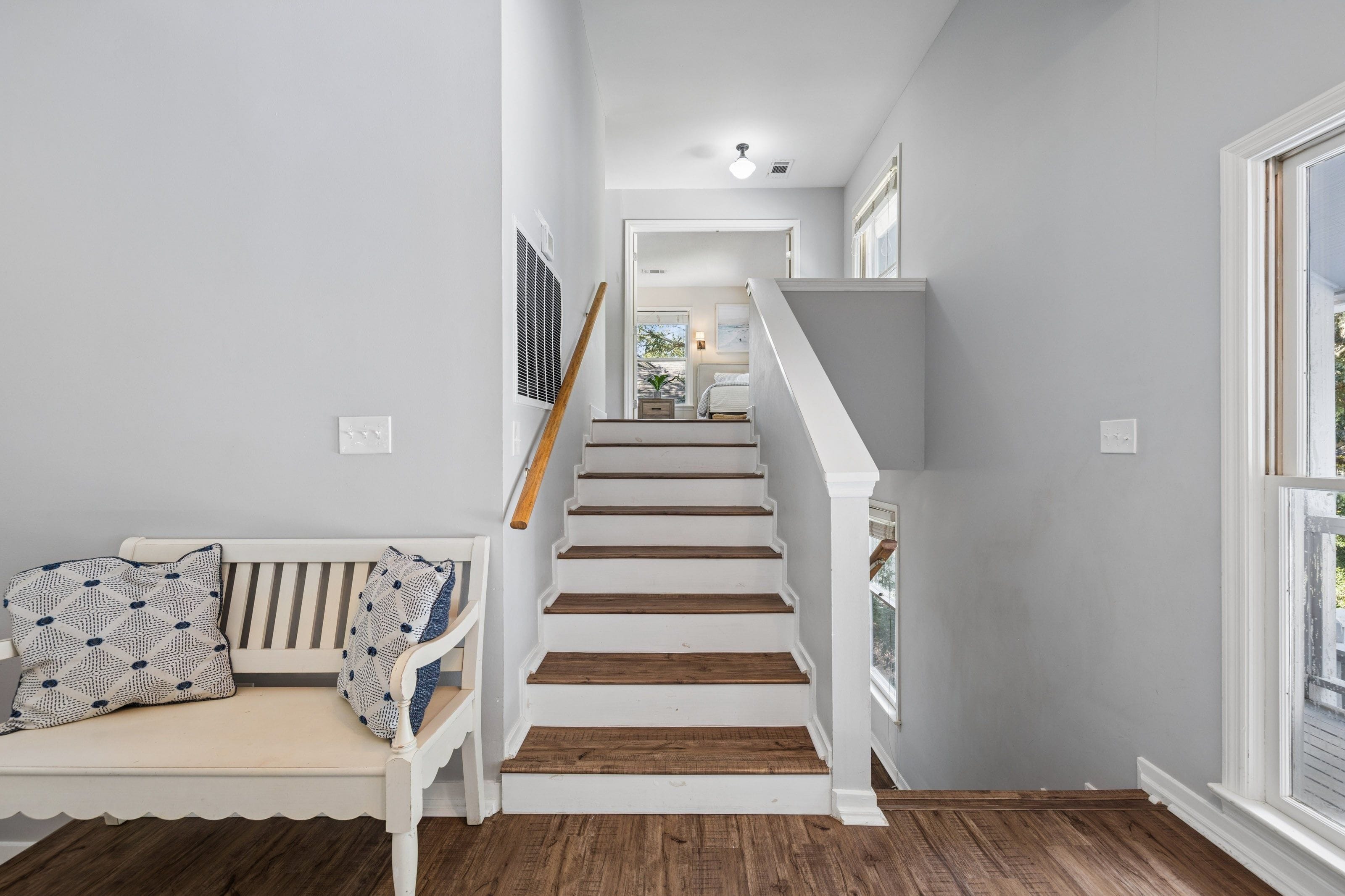 Una escalera de madera con barandillas blancas que lleva a un piso superior.