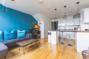 Eine moderne Wohnung mit Wohnbereich, Küchenzeile und Essplatz.
