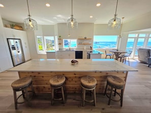 Cozinha moderna com uma ilha grande, banquetas e vista para o oceano.