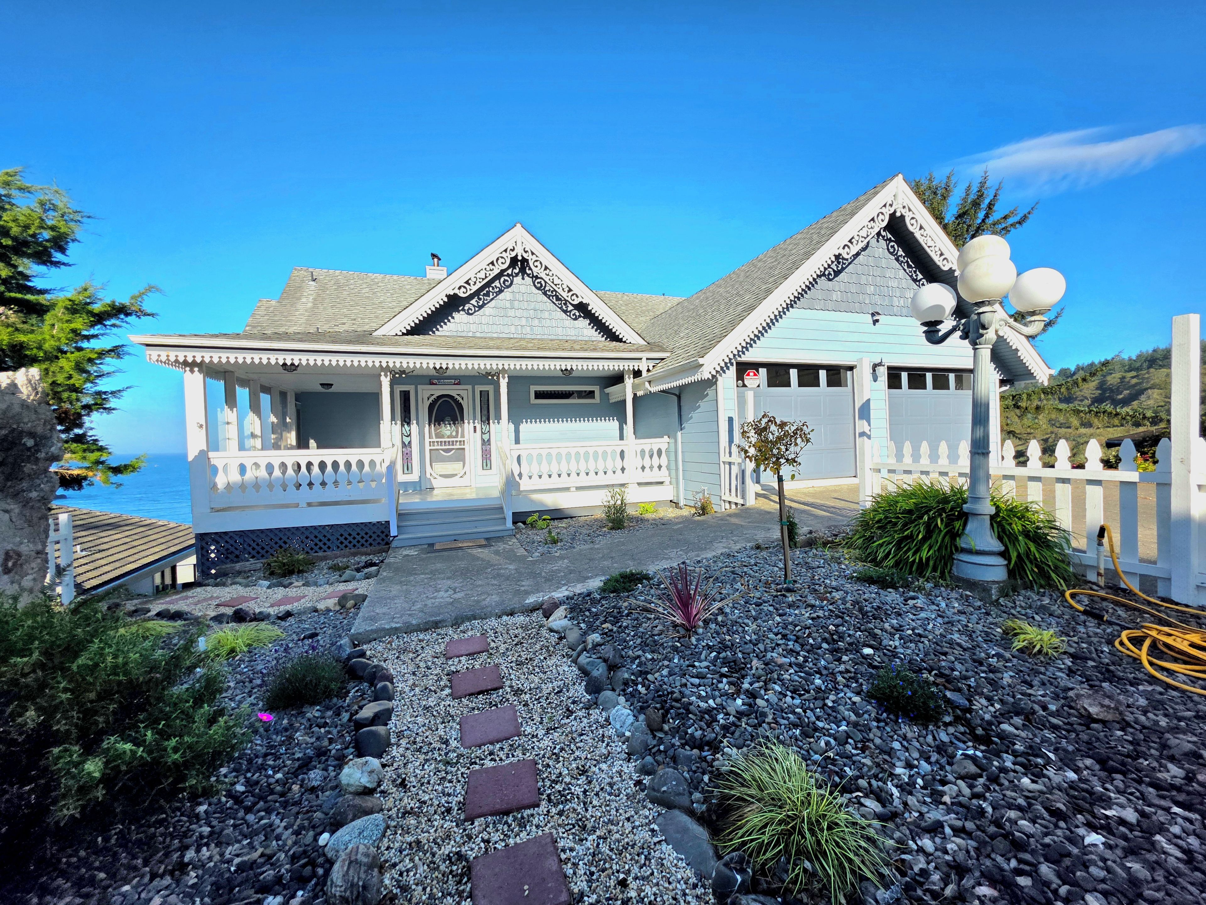 A coastal house with a porch, a garage, and a pathway leading to the entrance.