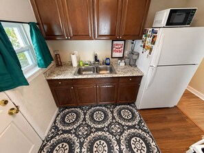 A kitchen with wooden cabinets, a double sink, a microwave, and a refrigerator.