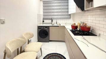 A compact kitchen with a washing machine, a stove, and a ceiling fan.