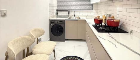 A compact kitchen with a washing machine, a stove, and a ceiling fan.