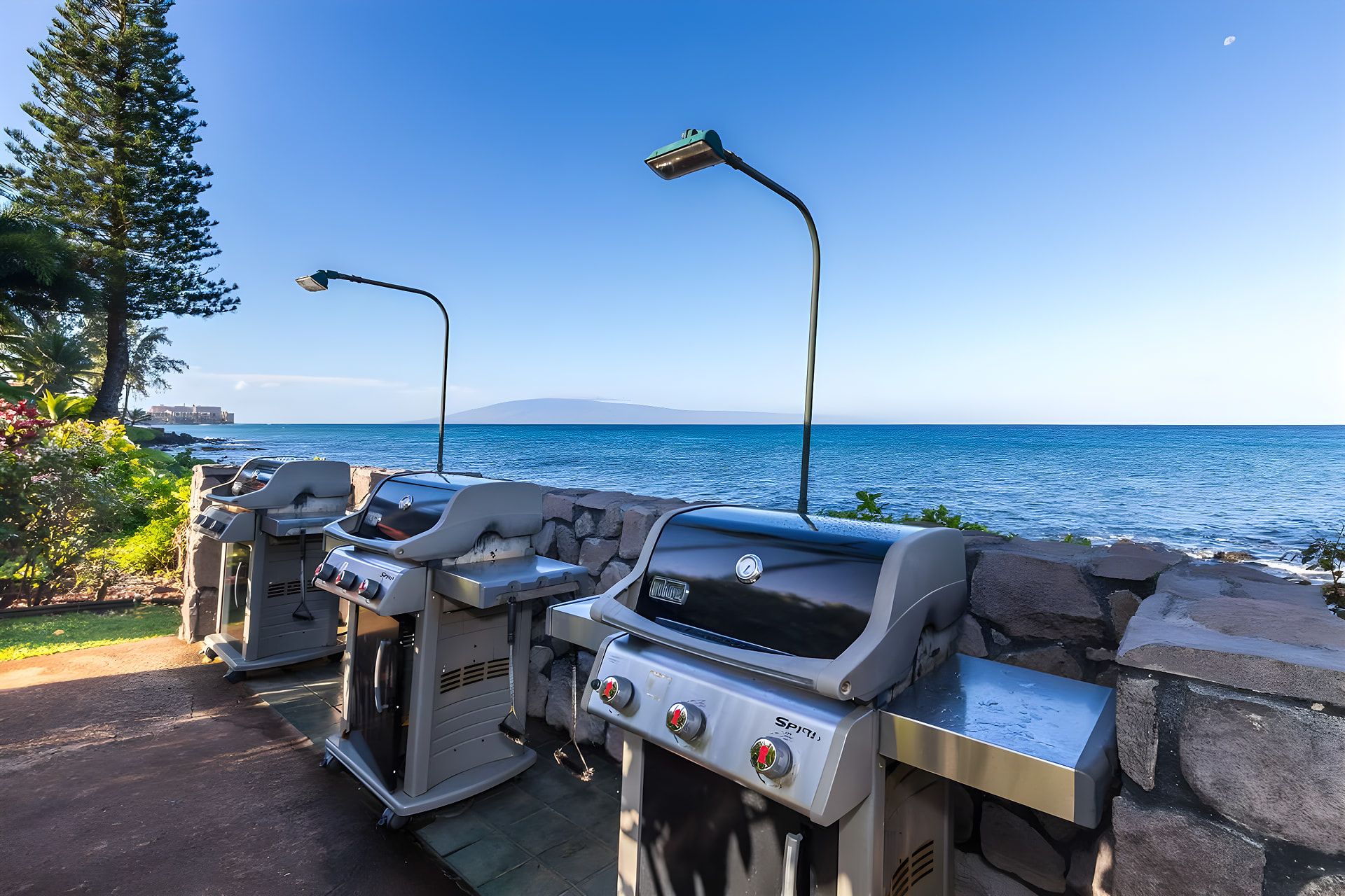 Barbecues buiten, aan zee, met uitzicht op de oceaan en een berg in de verte.