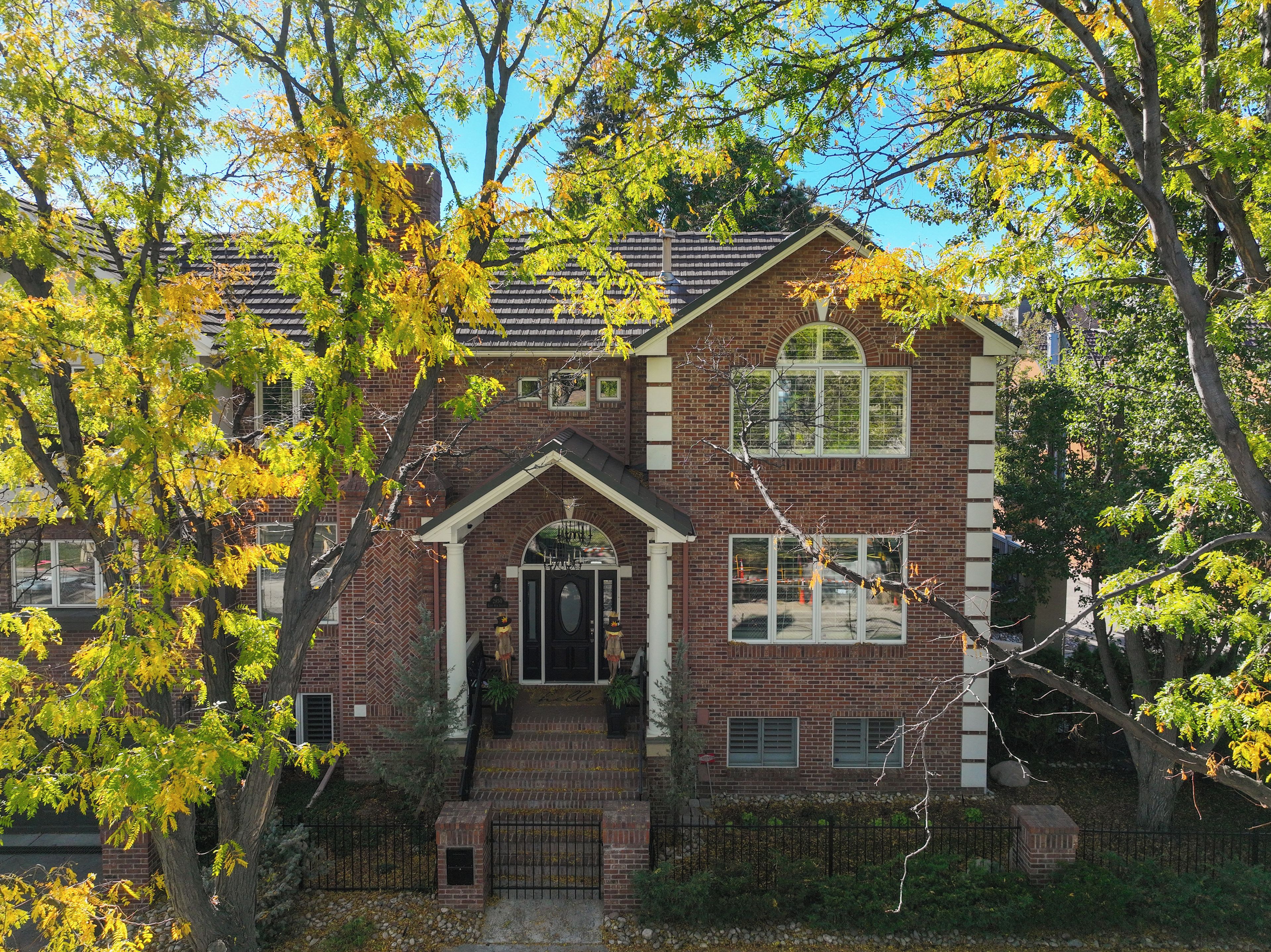 A two-story brick house with a central entrance, a front porch, and a small front yard.