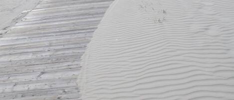 A wooden boardwalk adjacent to a sandy area with ripples.