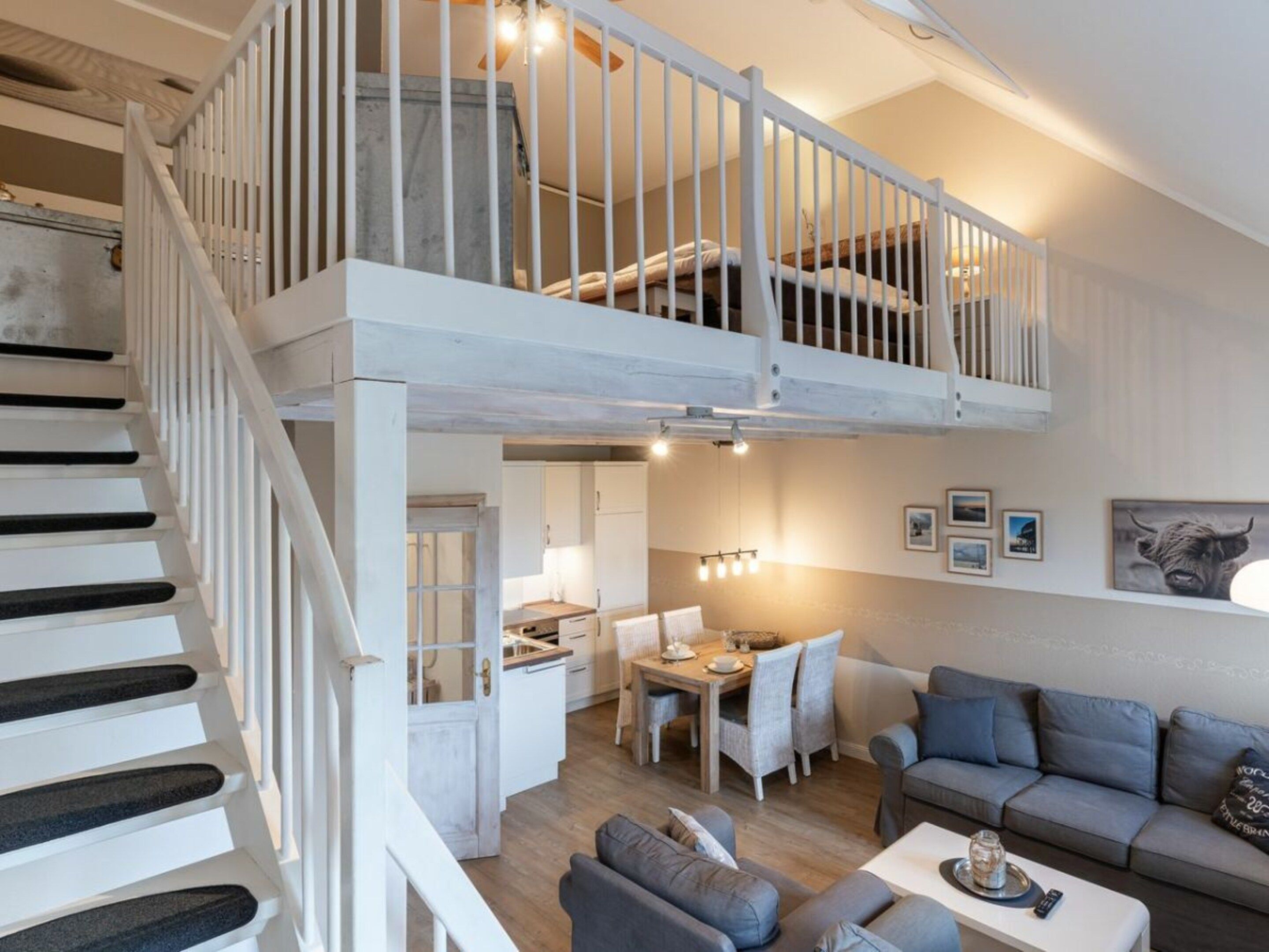 A spacious living area with a high ceiling, a staircase, a dining area, and a seating area with a sofa and a coffee table.