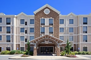 A multi-story hotel with a central entrance featuring a stone facade and a decorative archway. - Suite w/ Kitchen & Breakfast | Near IND Airport (Plainfield)