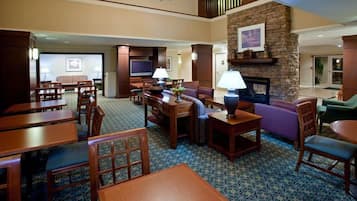 A hotel lobby with a fireplace, seating area, and a television.
