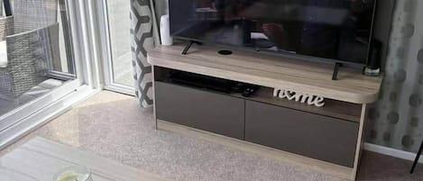 Una sala de estar con un televisor de pantalla plana grande, una mesa de centro de madera y un tapete estampado.