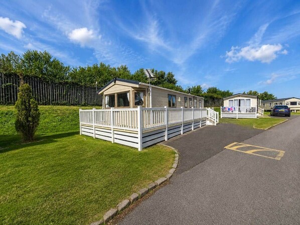 A caravan park with a single caravan, a paved road, and a grassy area. - The Retreat Anchorage – 8-Berth Caravan (Rhyl)