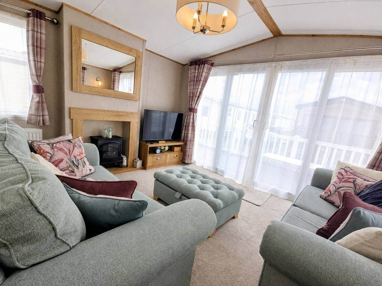 Una sala de estar con chimenea, televisión y ventanas amplias.