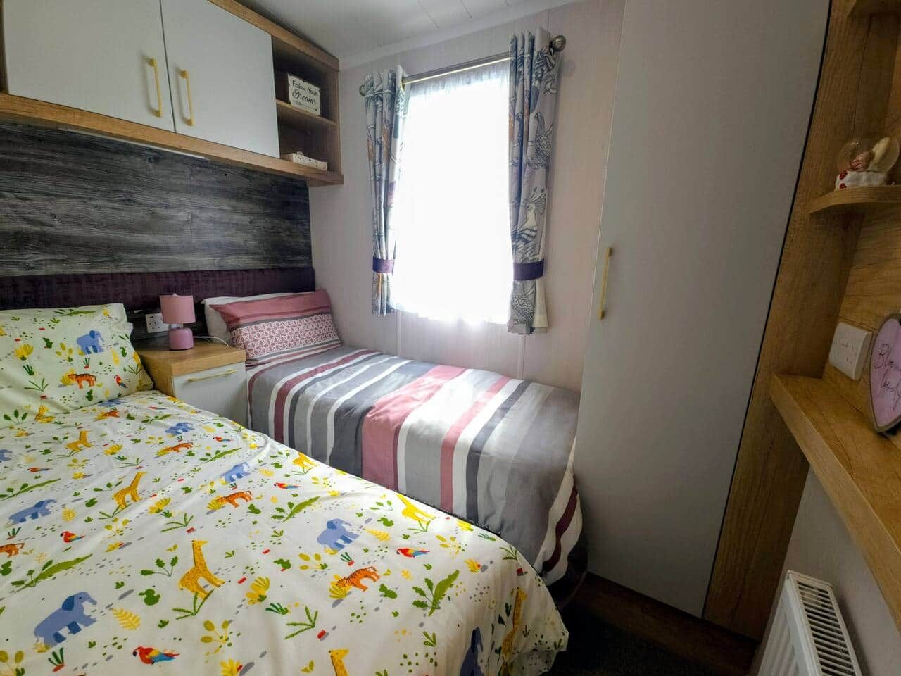 A bedroom with a bed, a nightstand, a dresser, and a window with curtains.