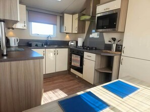 Cozinha compacta com fogão, micro-ondas e armários.