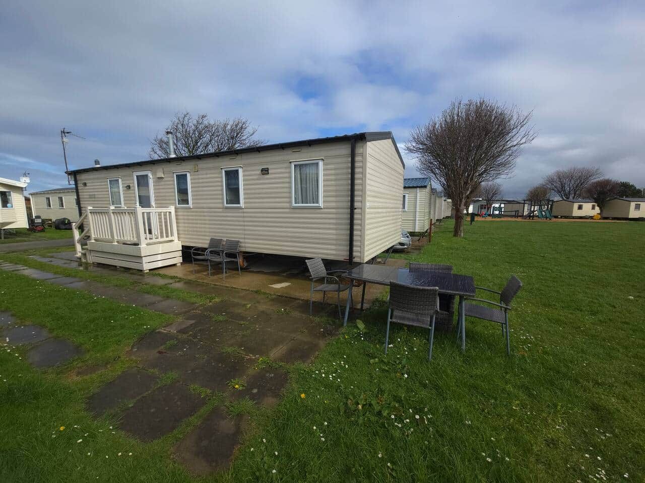 A mobile home with a patio area, a small table, and chairs.