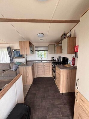 Una cocina compacta con muebles de madera, una estufa y un lavamanos.