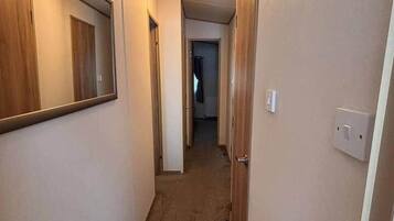 En smal gang med tæppebelagte gulve, trædøre og en lampe i loftet.