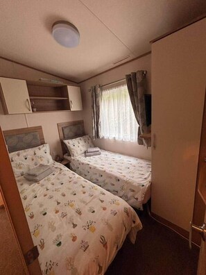 Una habitación con dos camas, un armario y una l ámpara en el techo.