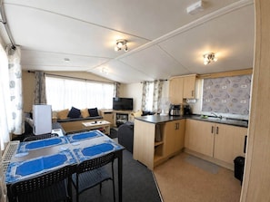 A compact RV interior with a dining area, kitchenette, and seating space. - The Retreat Prestatyn Beach – 3-Bed (Prestatyn)