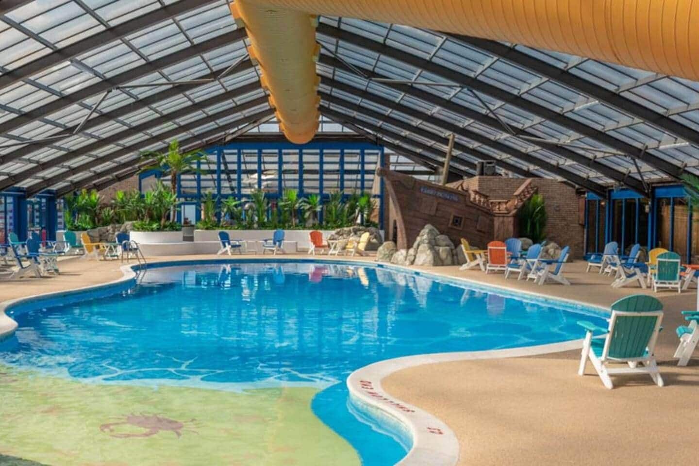 Una piscina interior con sillones de descanso y temática tropical.