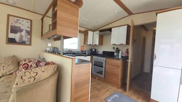 Eine kleine Küche mit Holzausstattung, einem Backofen und einem Essbereich mit einer Sitzecke.