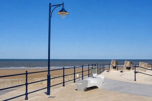 A seaside promenade with a metal railing, a street lamp, and benches. - The Retreat Sunhaven – 7-Berth (Prestatyn)