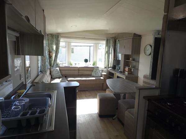 Ein kompaktes Wohnmobil-Interieur mit einer Küchenzeile, einer Essecke und einer Sitzecke mit Aussicht.