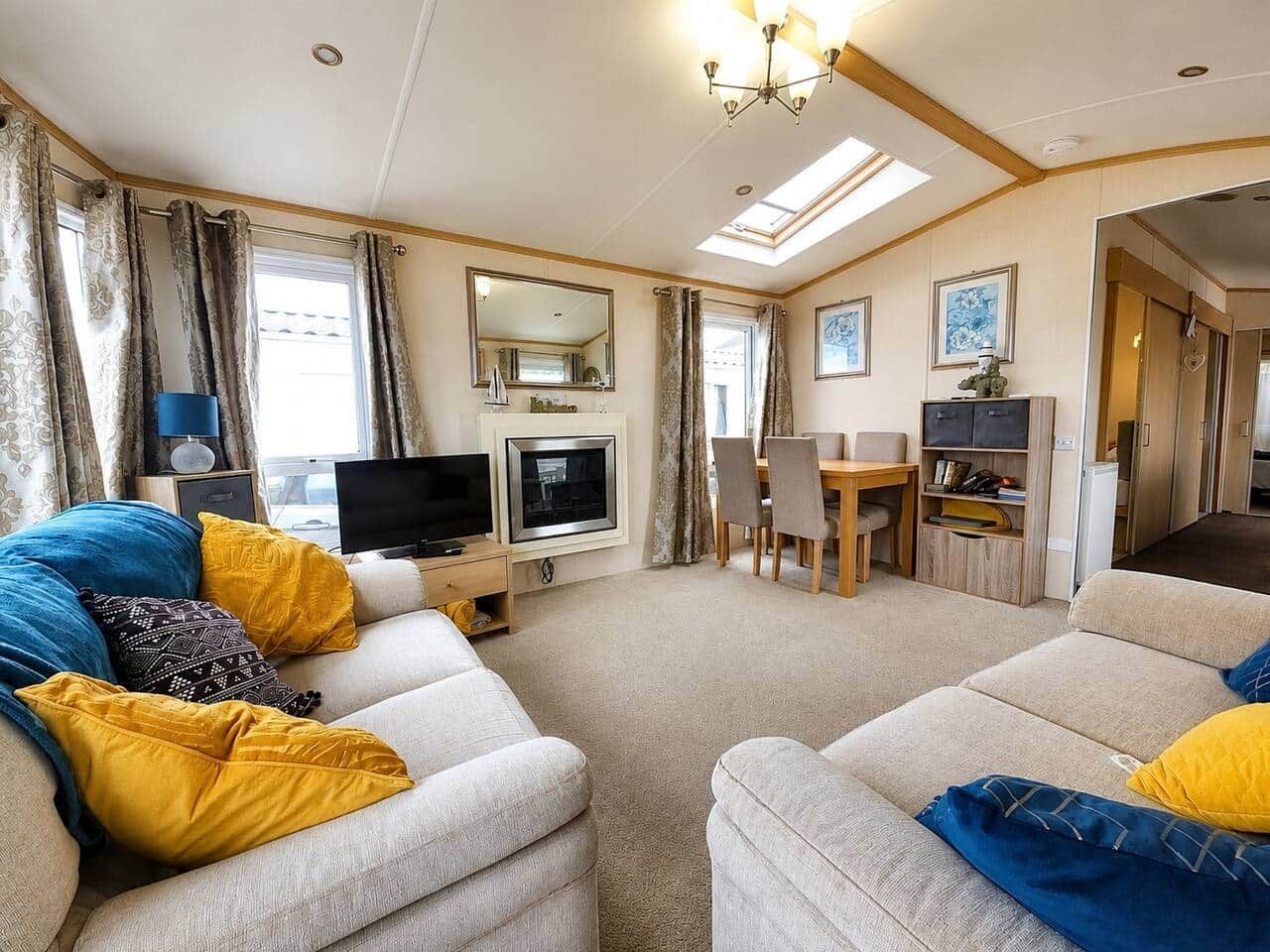 A living room with sofas, a television, a dining area, and a kitchen in the background.