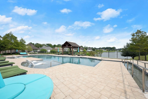 A swimming pool with lounge chairs and a gazebo.