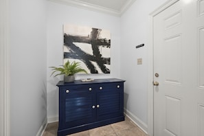 Ein Flur mit einem dunkelblauen Schrank, einer Topfpflanze und einem großen abstrakten Gemälde an der Wand.