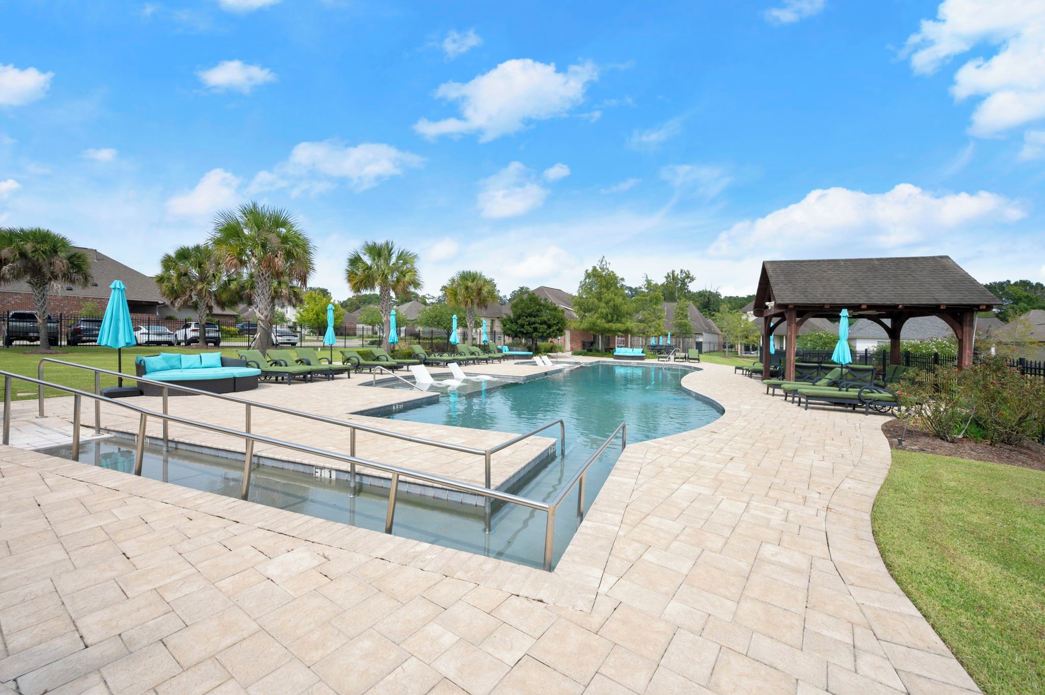 Une piscine entourée d’une terrasse, de chaises longues et d’un belvédère.