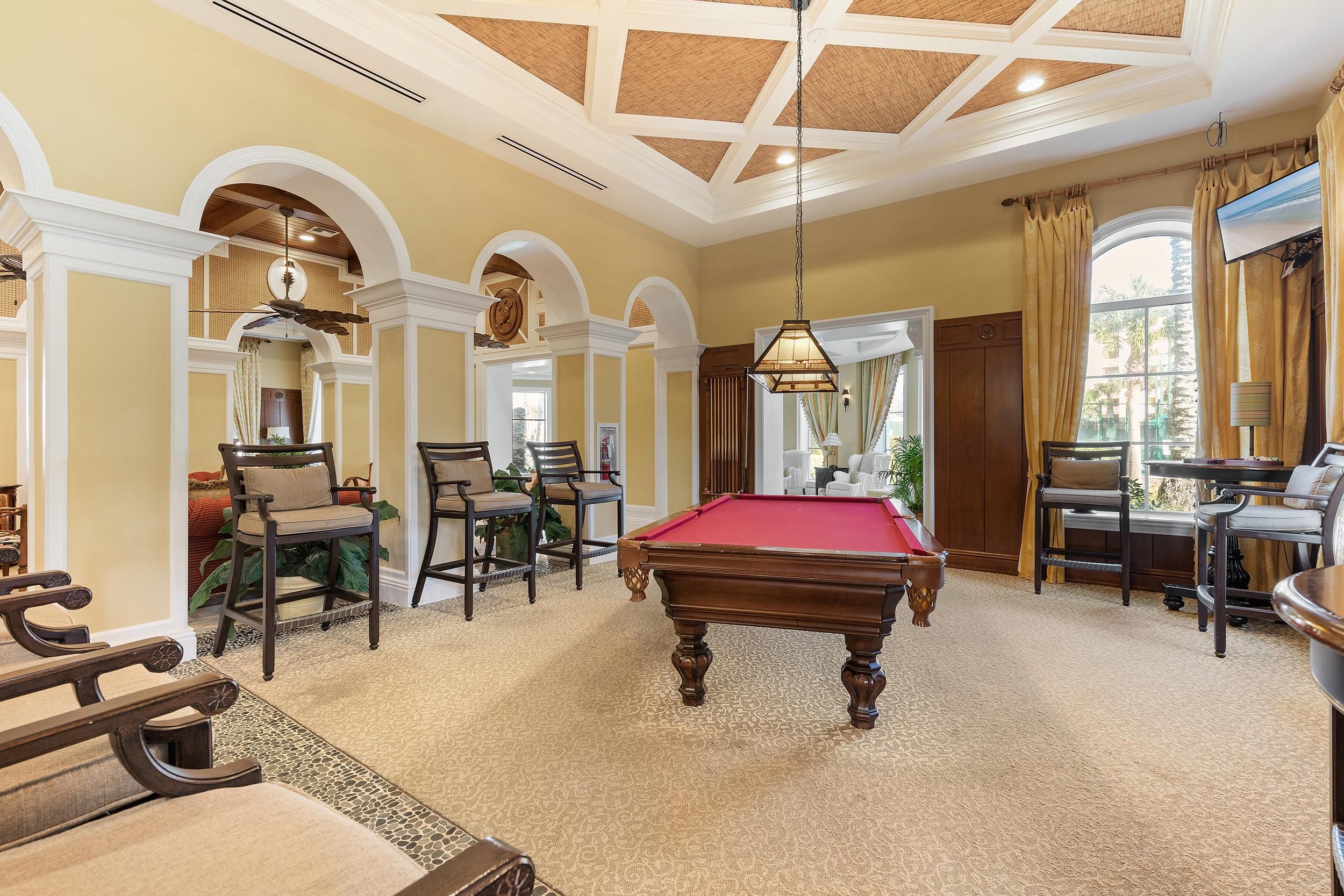 Une pièce spacieuse équipée d’une table de billard, de sièges confortables et d’une grande fenêtre donnant sur l’extérieur.