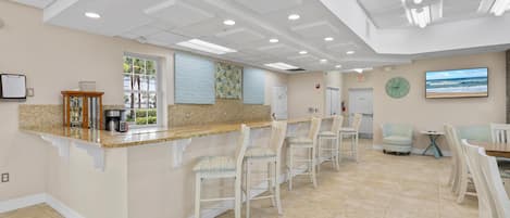 A spacious kitchen area with a long counter, multiple bar stools, and a seating area with chairs and a small table.
