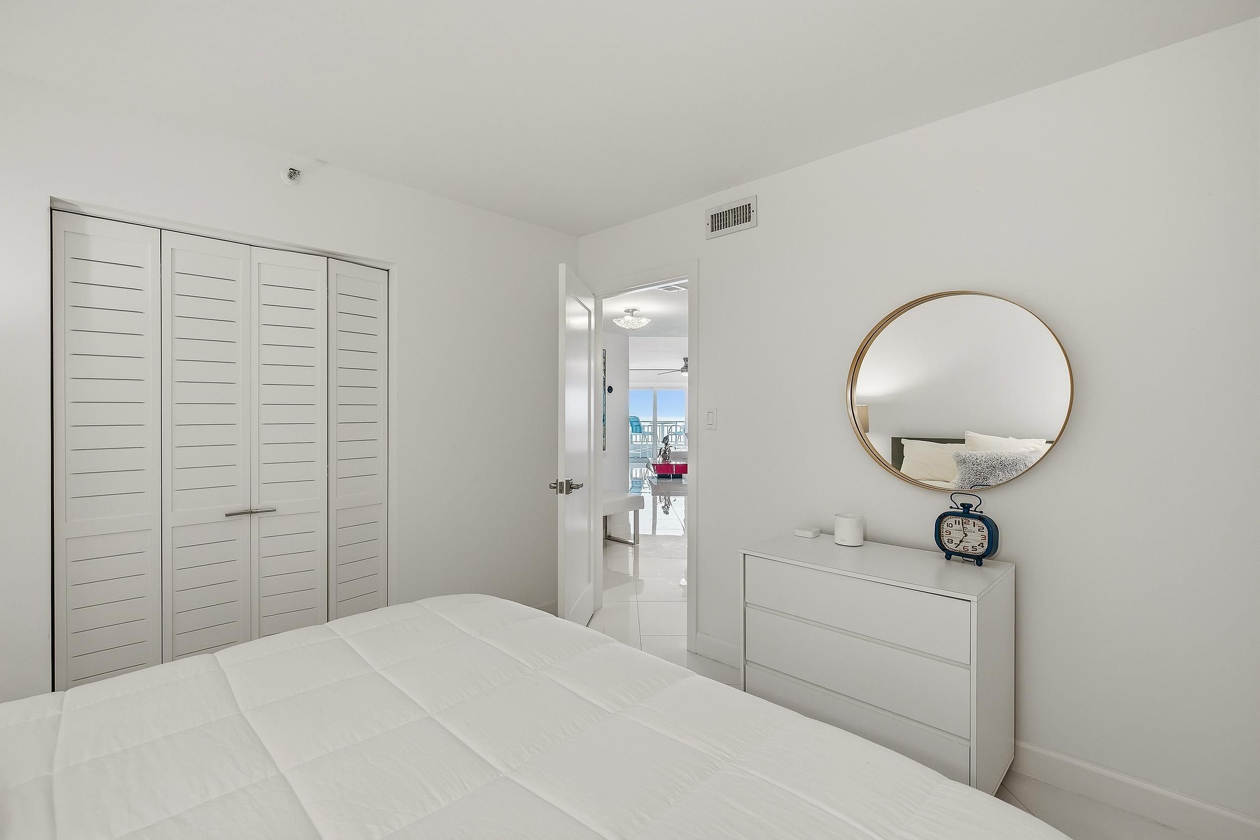 Une chambre à coucher avec un lit, une commode, un miroir et une armoire.