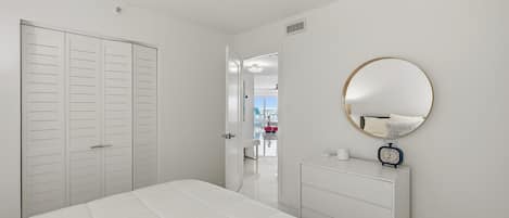 A bedroom with a bed, a dresser, a mirror, and a wardrobe.