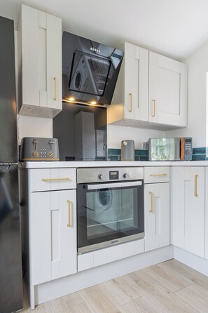 A modern kitchen with white cabinetry, stainless steel appliances, and a built-in oven. - House in Bury w/ Pool Table - Sleeps 6 (Greater Manchester)