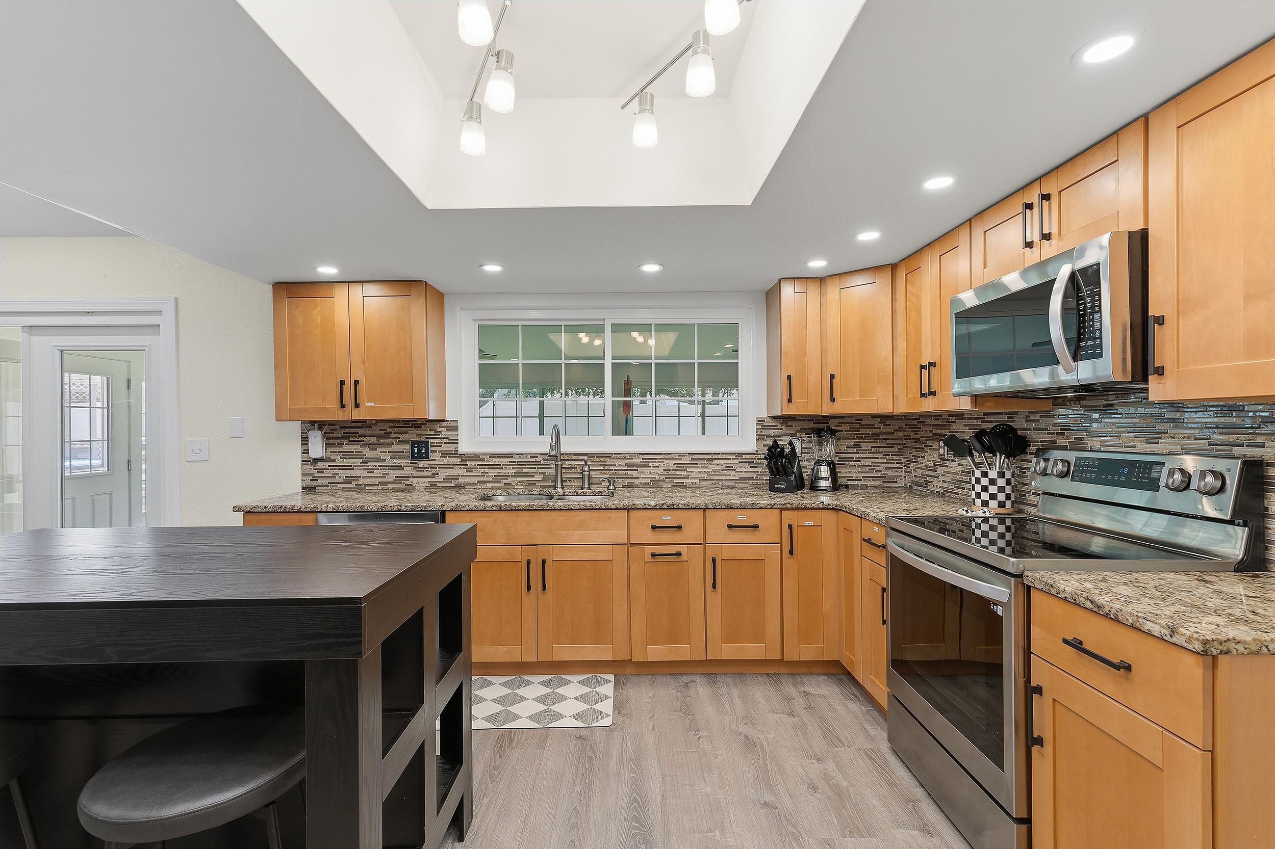 A modern kitchen with wooden cabinets, a granite countertop, and stainless steel appliances.