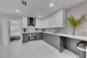 A modern kitchen with white cabinetry, a built-in oven, and a large window.