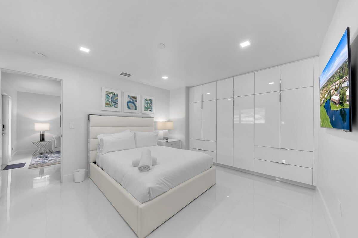 A modern bedroom with a large bed, a wardrobe, and a flat-screen TV.