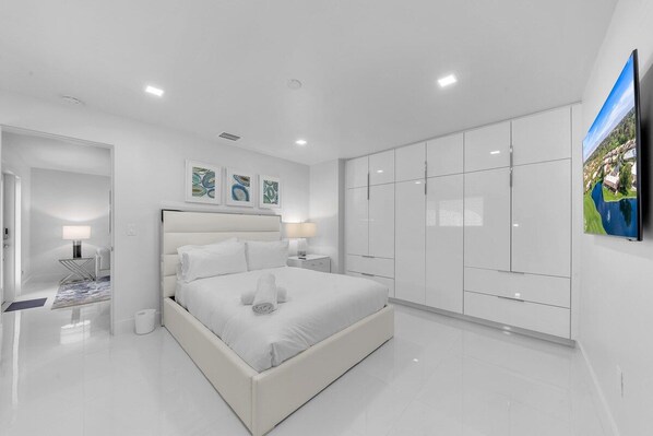 A modern bedroom with a large bed, a wardrobe, and a flat-screen TV.