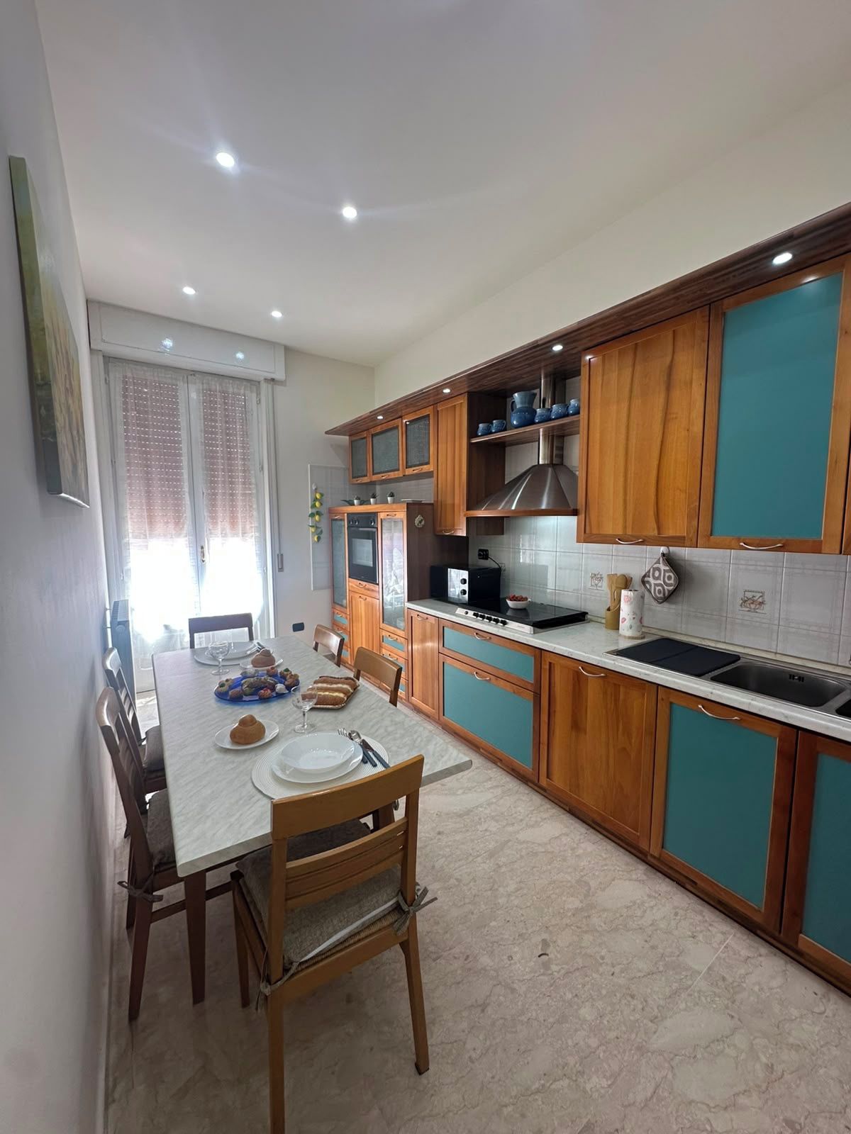 Una cucina moderna con mobili in legno, un tavolo da pranzo per quattro persone e un forno integrato.
