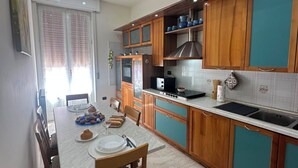 A modern kitchen with wooden cabinets, a dining table set for four, and a built-in oven. - "Cantarà Guest House"—a vacation rental in the center of Pachino, near the beach (Pachino)