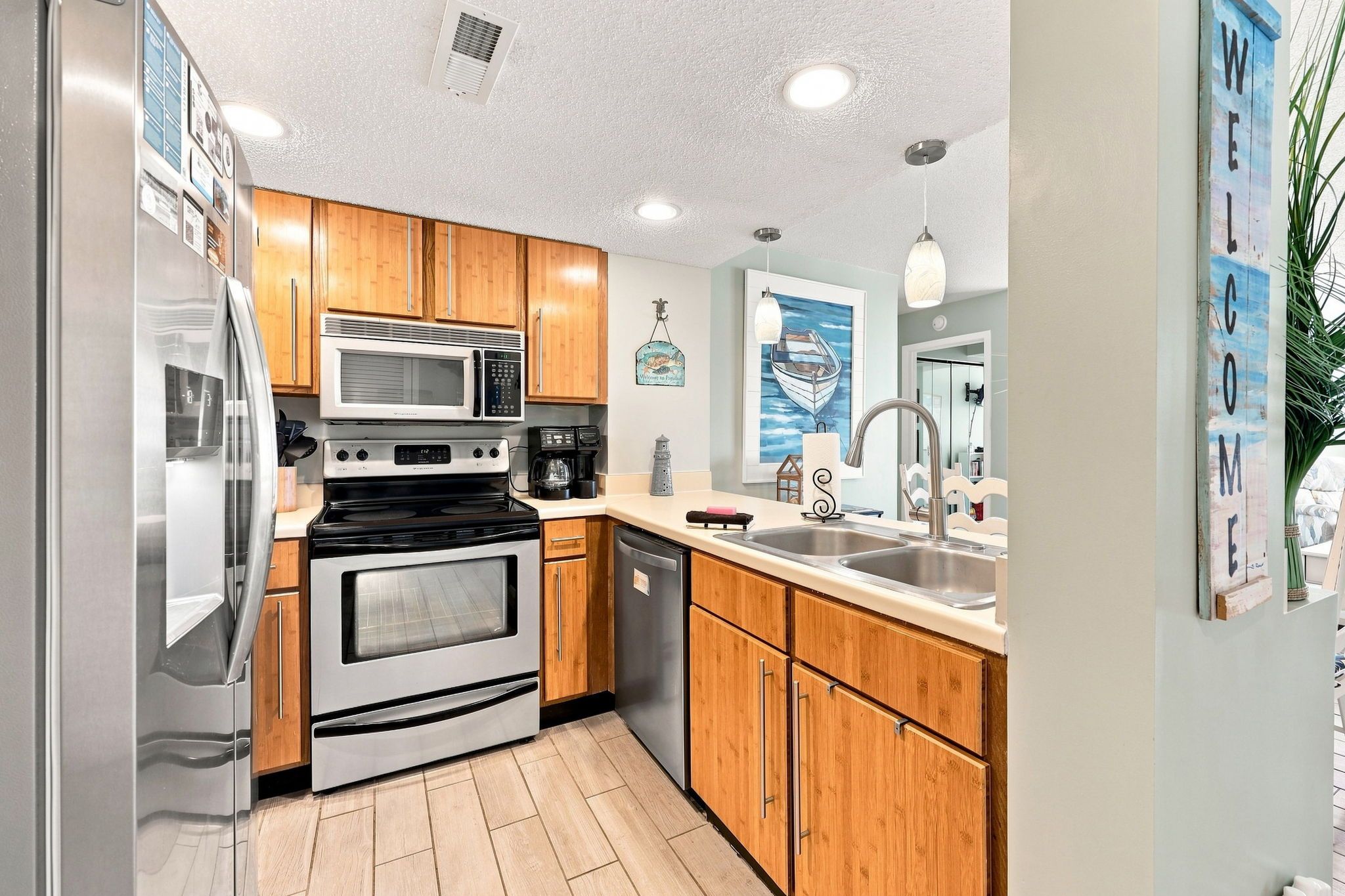 A modern kitchen with stainless steel appliances, wooden cabinets, and a large window.