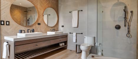 A modern bathroom with a wooden wall, two sinks, a large mirror, a bathtub, and a shower.